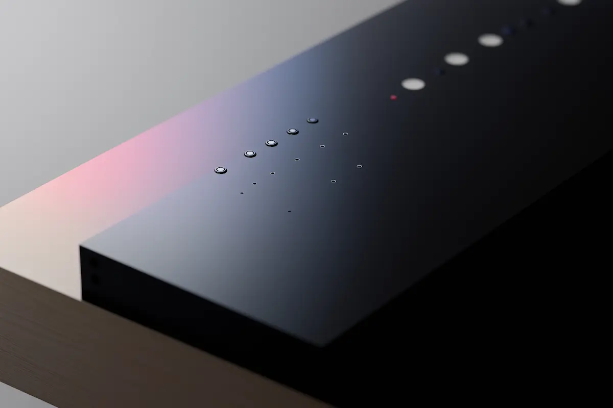 Close-up of a sleek black electronic device with a glossy surface and circular buttons in a row.